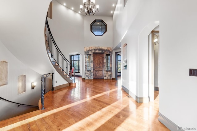5810 Amber Ridge Dr, Castle Pines, CO 80108 - foyer with arched walkways, wood finished floors, a chandelier, a high ceiling, and stairway