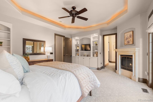 5810 Amber Ridge Dr, Castle Pines, CO 80108 - bedroom featuring a tray ceiling, light carpet, a lit fireplace, and baseboards