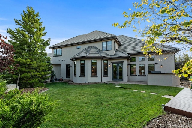 5810 Amber Ridge Dr, Castle Pines, CO 80108 - rear view of house with french doors, stucco siding, a lawn, and a tile roof