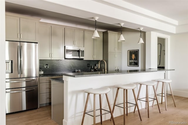8937 Little Raven Trl, Niwot, CO 80503 - kitchen featuring stainless steel appliances, a breakfast bar area, tasteful backsplash, light wood-style floors, and hanging light fixtures