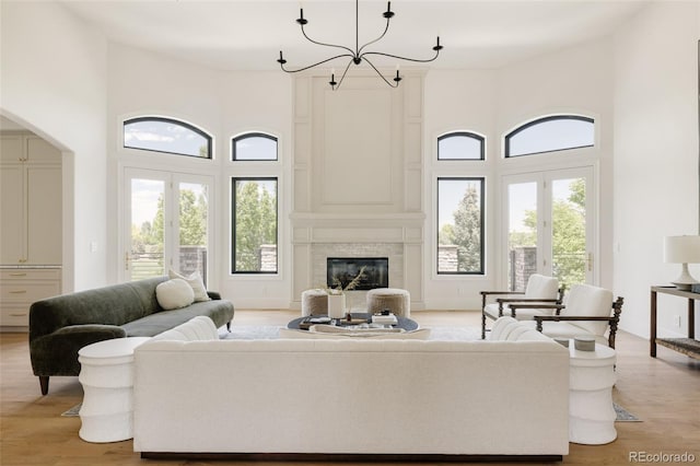 8937 Little Raven Trl, Niwot, CO 80503 - living area featuring a towering ceiling, light wood finished floors, a chandelier, arched walkways, and french doors