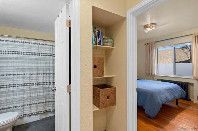 bedroom featuring radiator and hardwood / wood-style floors