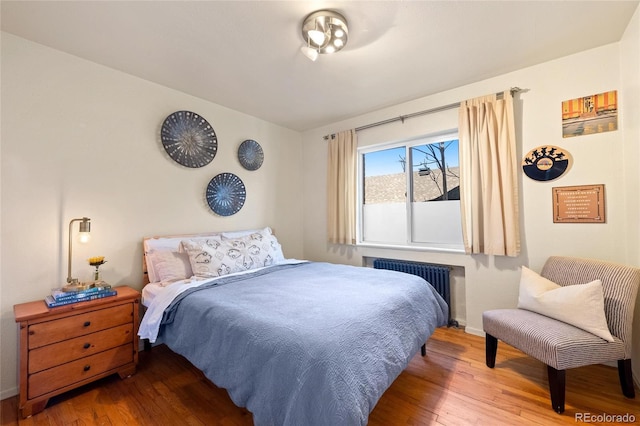 bedroom featuring radiator and hardwood / wood-style flooring