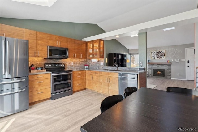 kitchen with decorative backsplash, open floor plan, vaulted ceiling, stainless steel appliances, and a sink