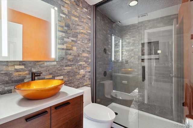 bathroom featuring tasteful backsplash, visible vents, toilet, a tile shower, and vanity