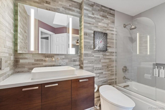 full bathroom featuring tasteful backsplash, toilet, enclosed tub / shower combo, vanity, and tile walls