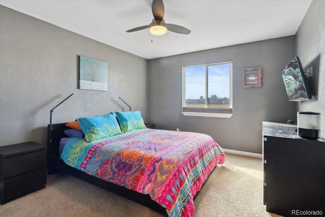 bedroom with a ceiling fan, light carpet, and baseboards