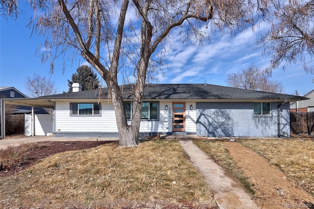 ranch-style home featuring a front lawn, fence, and an attached carport