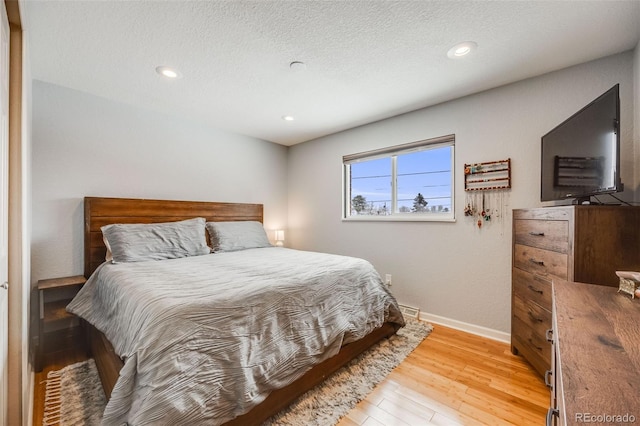 bedroom featuring a textured ceiling, baseboards, wood finished floors, and recessed lighting