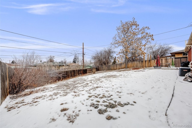 snowy yard with central AC and fence