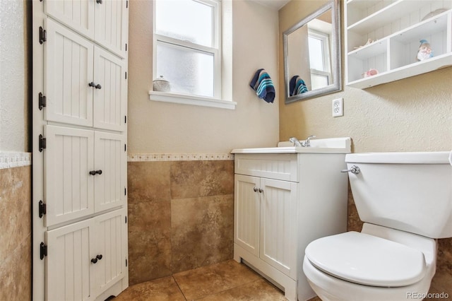 11855 Humboldt Dr, Northglenn, CO 80233 - bathroom featuring tile walls, vanity, tile patterned floors, and a wainscoted wall