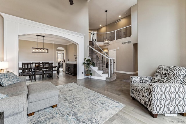 living area with a chandelier, wood finished floors, visible vents, and stairs