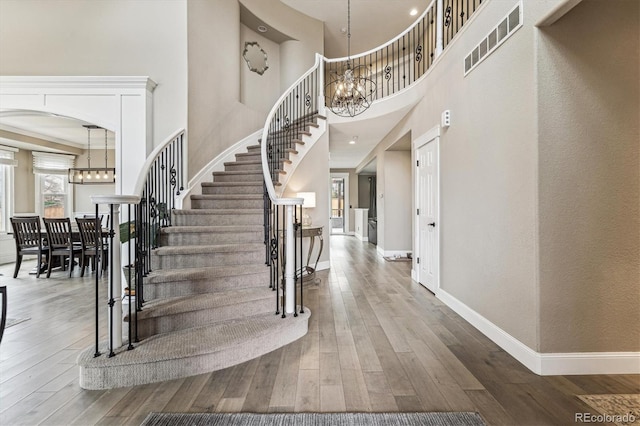 entryway with hardwood / wood-style floors, visible vents, and a notable chandelier