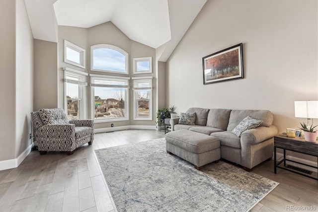 living room with high vaulted ceiling, baseboards, and wood finished floors