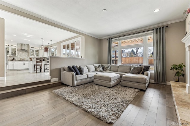 living room with light wood-style flooring, baseboards, crown molding, and recessed lighting