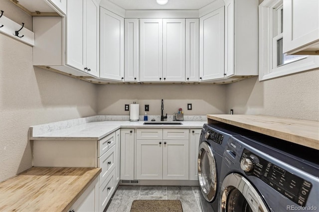 laundry area featuring wood finish floors, a sink, visible vents, cabinet space, and washing machine and clothes dryer