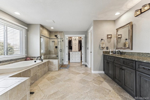 full bath featuring a garden tub, a spacious closet, a shower stall, vanity, and baseboards