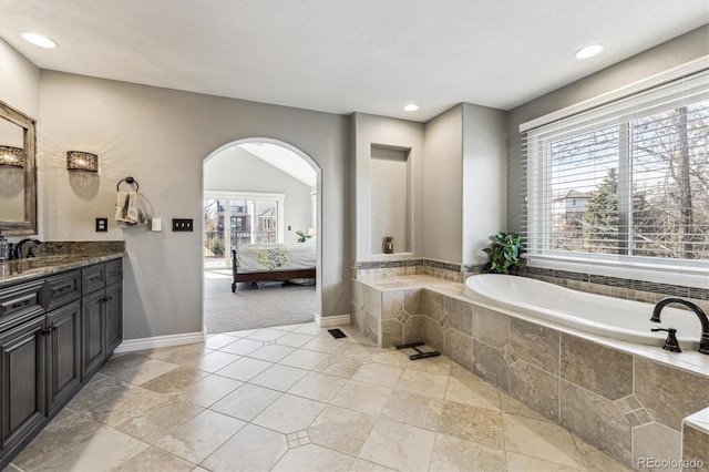 ensuite bathroom featuring baseboards, ensuite bath, vanity, a bath, and recessed lighting