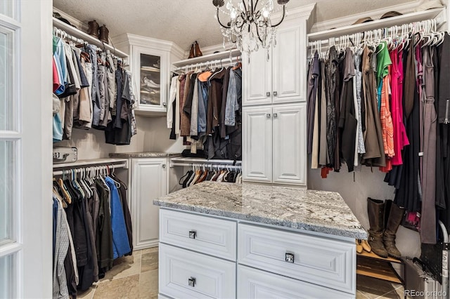 spacious closet featuring stone finish floor and a notable chandelier