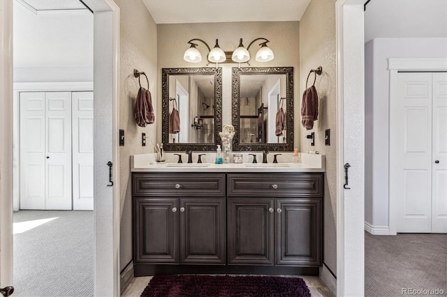 full bathroom featuring a textured wall, double vanity, a closet, and a sink