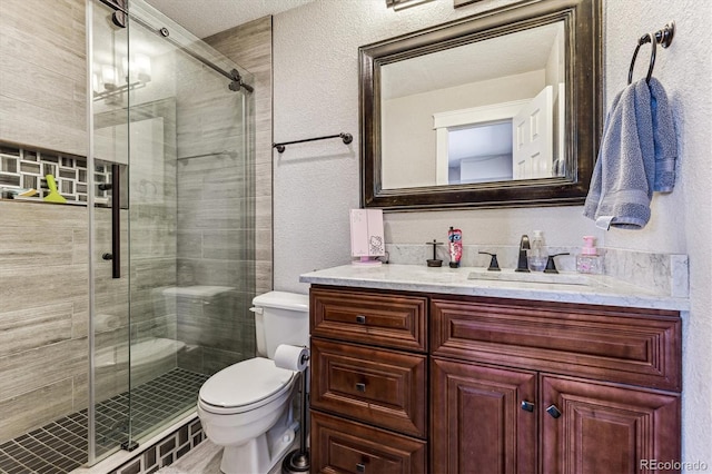 full bathroom featuring toilet, a textured wall, a shower stall, and vanity