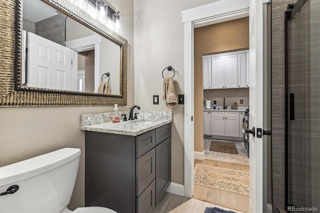 bathroom featuring toilet, a textured wall, wood finished floors, and vanity