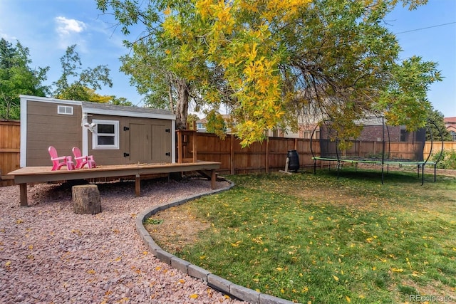 view of yard featuring a fenced backyard, a trampoline, a storage unit, and an outbuilding