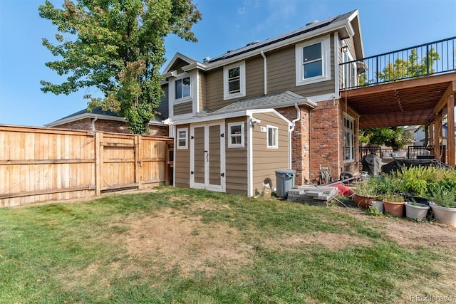 rear view of house with a yard, brick siding, and fence