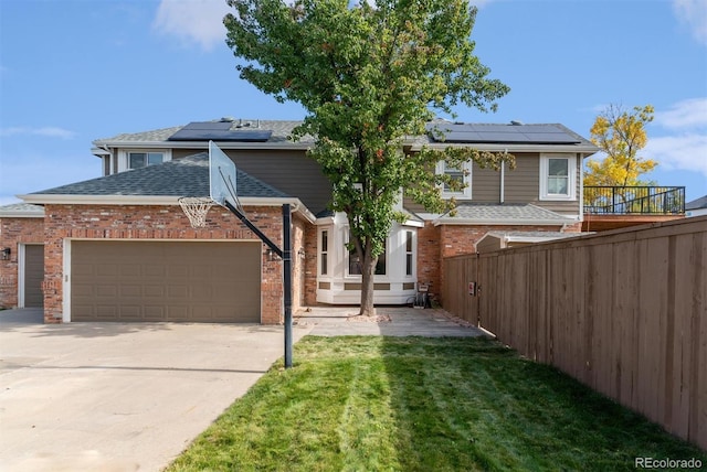 view of front of home with an attached garage, fence, a front lawn, and solar panels