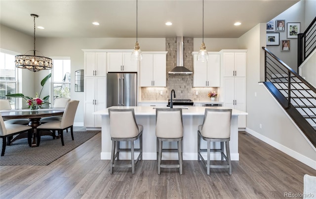 6235 Stable View St, Castle Pines, CO 80108 - kitchen with wall chimney range hood, high end fridge, a center island with sink, light countertops, and a kitchen breakfast bar