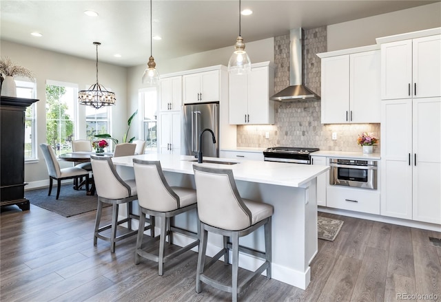6235 Stable View St, Castle Pines, CO 80108 - kitchen featuring wall chimney exhaust hood, appliances with stainless steel finishes, an island with sink, a breakfast bar, and dark wood finished floors