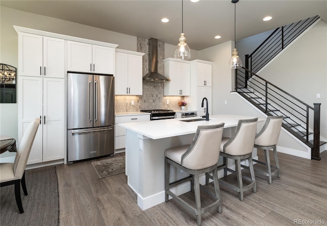 6235 Stable View St, Castle Pines, CO 80108 - kitchen with stainless steel appliances, wall chimney exhaust hood, wood finished floors, a center island with sink, and decorative backsplash
