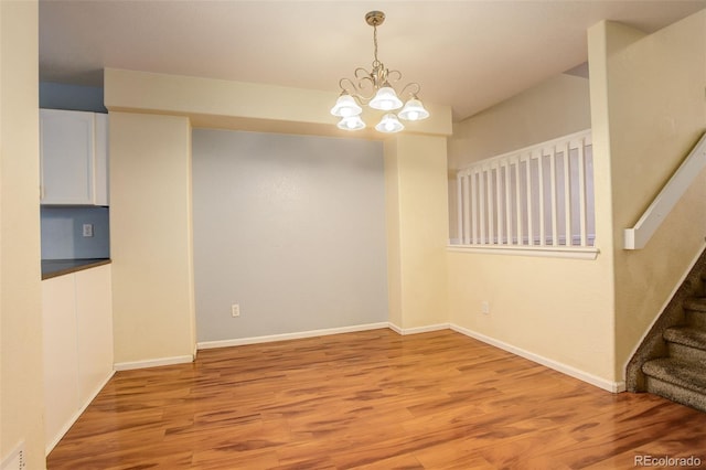 unfurnished dining area featuring an inviting chandelier and light hardwood / wood-style floors