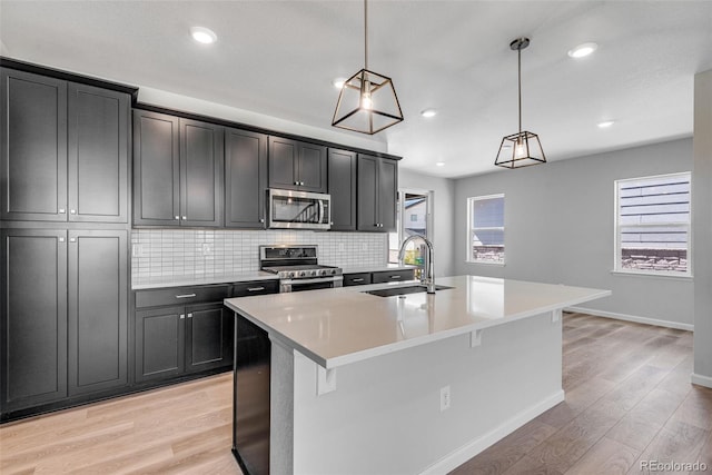3314 N Haleyville Ct, Aurora, CO 80019 - kitchen with appliances with stainless steel finishes, a sink, tasteful backsplash, light wood-type flooring, and a kitchen island with sink