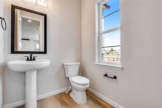 3314 N Haleyville Ct, Aurora, CO 80019 - half bathroom featuring baseboards, wood finished floors, toilet, and plenty of natural light