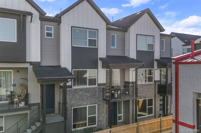 townhome / multi-family property featuring fence, board and batten siding, and brick siding