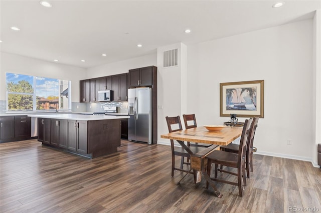 kitchen with visible vents, a kitchen island, stainless steel appliances, dark brown cabinets, and light countertops