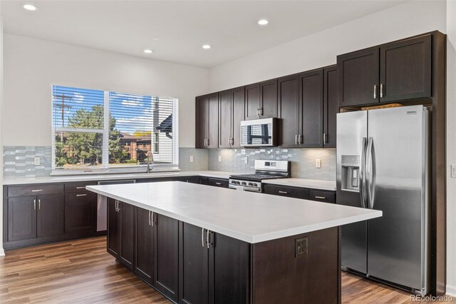 kitchen featuring stainless steel appliances, a center island, light countertops, and dark brown cabinets