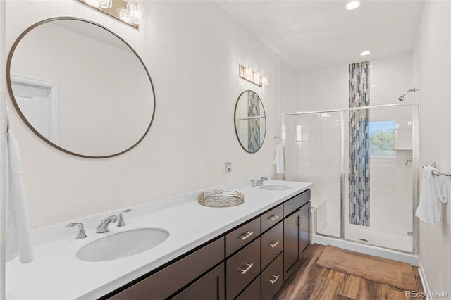 full bath featuring a stall shower, double vanity, a sink, and wood finished floors