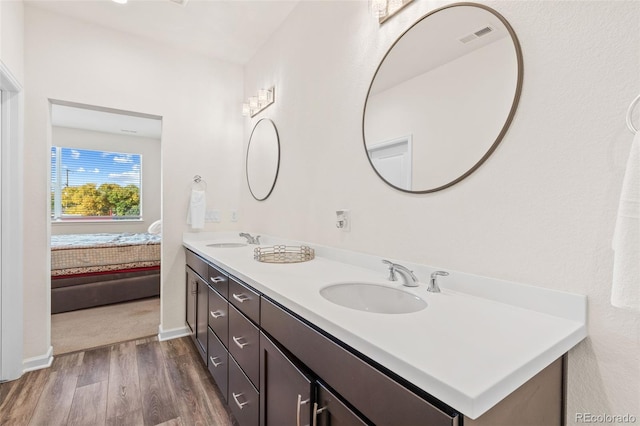 full bathroom featuring double vanity, wood finished floors, a sink, and connected bathroom