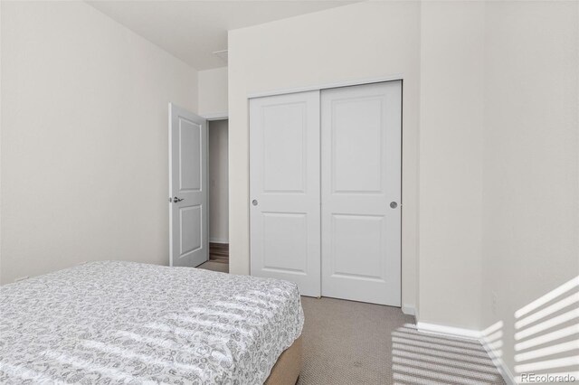 bedroom with baseboards, a closet, and light colored carpet