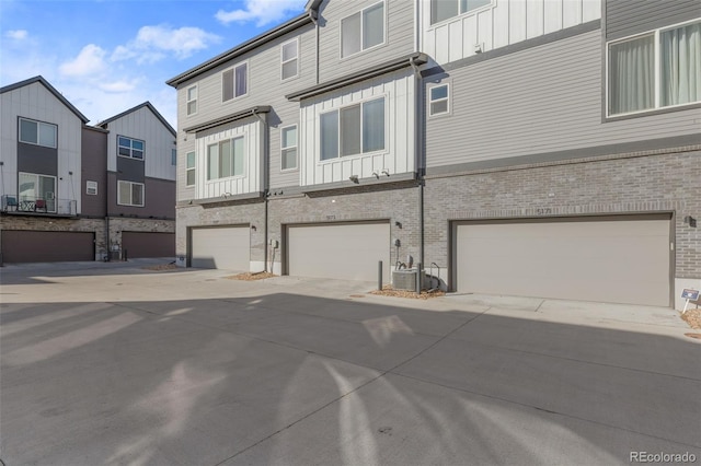 exterior space featuring an attached garage, central AC, a residential view, and board and batten siding