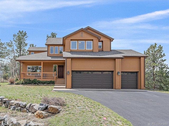 3173 Gold Yarrow Ln, Evergreen, CO 80439 - view of front facade featuring an attached garage, a front lawn, covered porch, and aphalt driveway