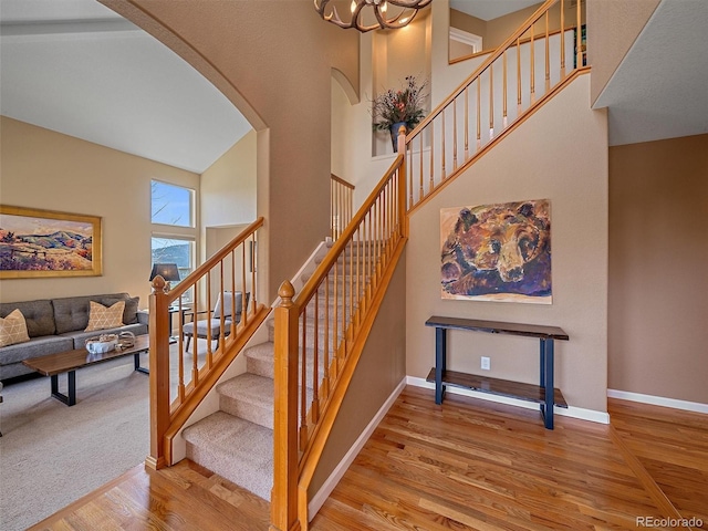 3173 Gold Yarrow Ln, Evergreen, CO 80439 - staircase featuring arched walkways, wood finished floors, a high ceiling, and baseboards
