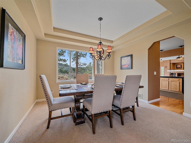 3173 Gold Yarrow Ln, Evergreen, CO 80439 - dining area with a chandelier, arched walkways, light carpet, a raised ceiling, and baseboards