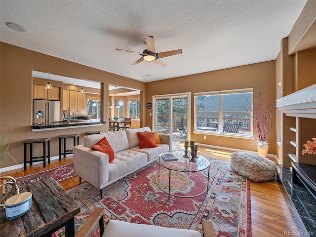 3173 Gold Yarrow Ln, Evergreen, CO 80439 - living room featuring ceiling fan, baseboards, wood finished floors, and a textured ceiling