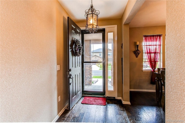 25120 E Maple Pl, Aurora, CO 80018 - entrance foyer featuring dark wood-type flooring, a textured wall, a chandelier, and baseboards