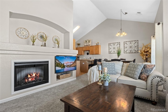 living area featuring a glass covered fireplace, a chandelier, high vaulted ceiling, and carpet floors