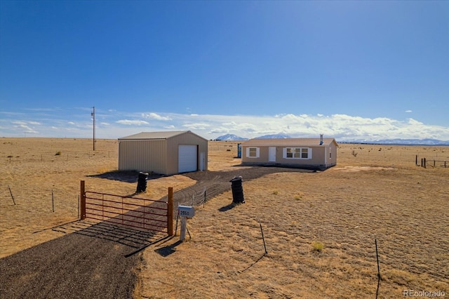 view of front of property with a garage, a rural view, fence, and an outdoor structure