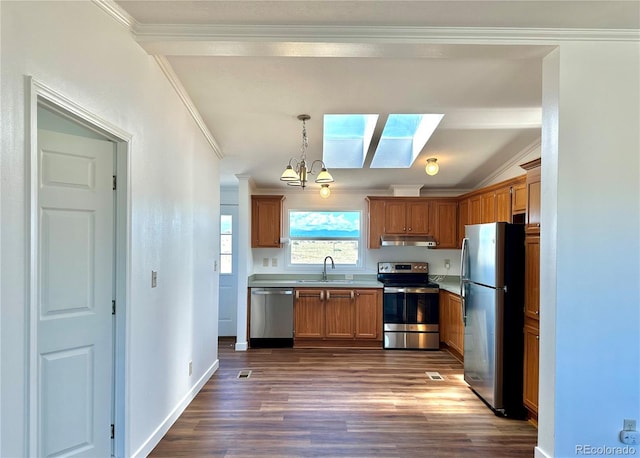 kitchen with under cabinet range hood, stainless steel appliances, dark wood-style flooring, a sink, and crown molding